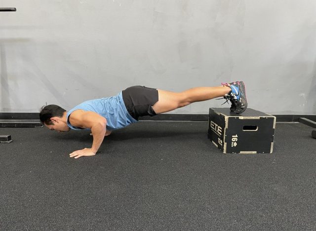 treinador fazendo flexões com os pés elevados, parte do treino para queimar gordura da barriga