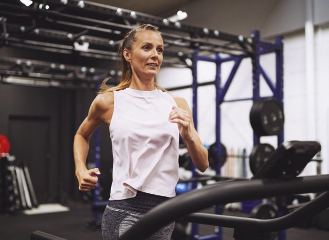 mulher madura fitness correndo na esteira na academia