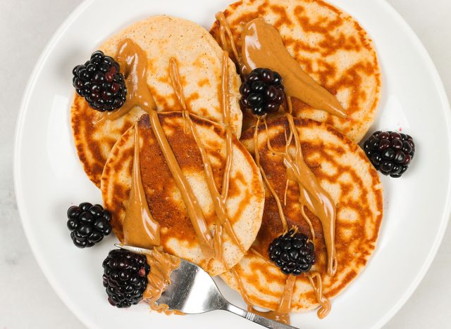 panquecas de proteína com manteiga de amendoim e amoras em um prato branco