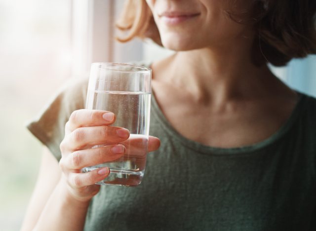 mulher de close-up segurando um copo de água, conceito de dicas de perda de gordura da barriga para mulheres